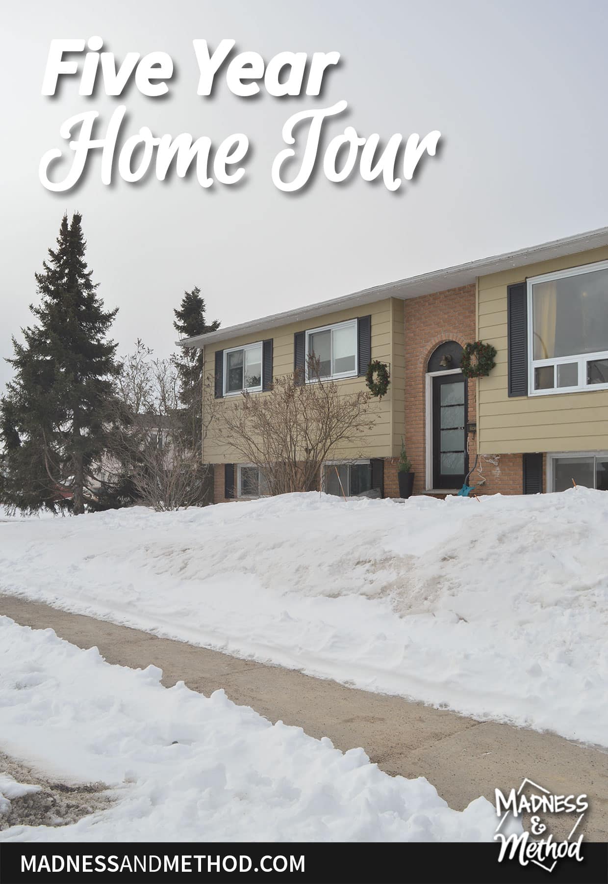 beige raised ranch house in snow with sidewalk